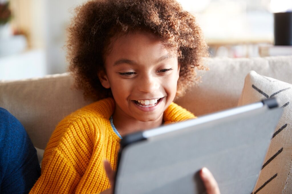 Portrait of pre-teen girl looking at tablet computer screen laughing, close up, selective focus